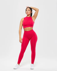 امرأة ترتدي قميص بدون أكمام Define Seamless Half Zip Crop باللون Viva Magenta من WOMEN'S BEST، مع سروال ضيق.