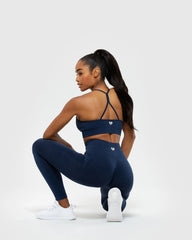 امرأة ترتدي حمالة صدر وسروالًا ضيقًا من نوع Sapphire Blue Define Seamless Racer Back وتؤدي تمرين القرفصاء بشكل مثالي، مما يدل على دعم ممتاز. (العلامة التجارية: وومن'س بيست)