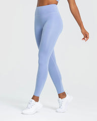 الوصف: سيدة ترتدي اليقطينة Essential Leggings الزرقاء الفاتحة والقميص الأبي. من أفضل النساء.