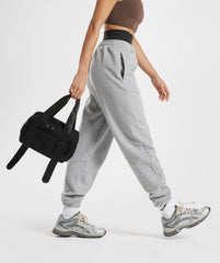الوصف: ملابس رياضية نسائية باللون الرمادي وحقيبة سوداء من SAUDI SHARK Everyday Mini Holdall.