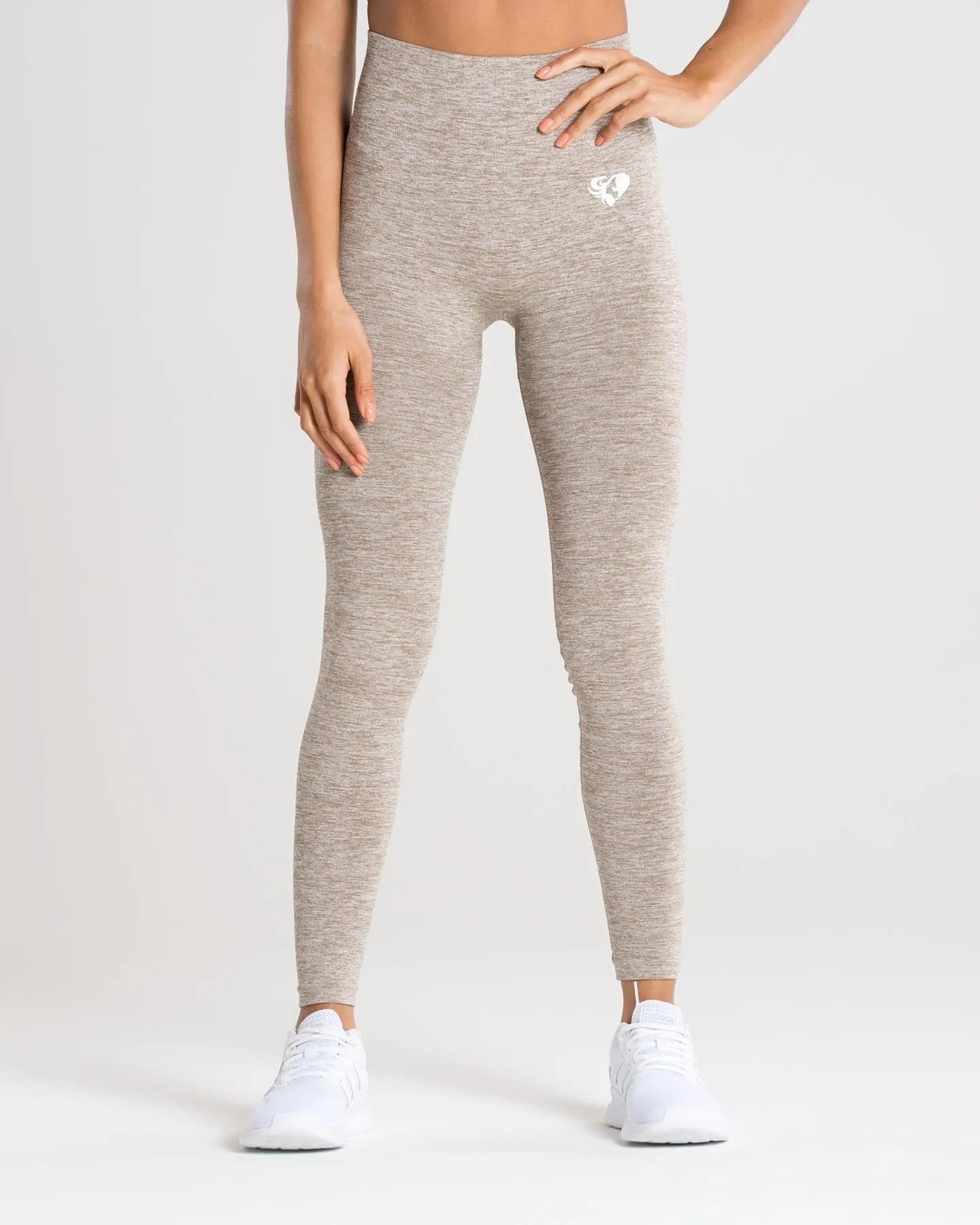 امرأة ترتدي بنطالًا ضيقًا باللون البيج وقميصًا أبيضًا، ينضح بنطال ضيق بدون خياطة من BEST WOMEN'S Move | براون غراي مارل و راحة.