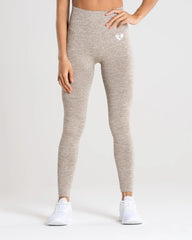 امرأة ترتدي بنطالًا ضيقًا باللون البيج وقميصًا أبيضًا، ينضح بنطال ضيق بدون خياطة من BEST WOMEN'S Move | براون غراي مارل و راحة.