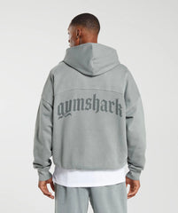 رجل يرتدي هوديي رمادي ثقيل الوزن من تصميم كلاسيكو مع كلمة Gymshark | يونايتد نحن نتعرق عليه.