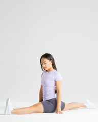 امرأة تؤدي تمرين القرفصاء على خلفية بيضاء، وتظهر مرونتها الناعمة وترتدي تي شيرت BEST Power Seamless للنساء باللون الأرجواني الفاتح للحصول على تهوية مثالية.