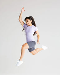 امرأة شابة ترتدي تي شيرت نسائي من ماركة Best Power Seamless Lilac تقفز في الهواء، لتستعرض الملمس الناعم ونعومة القماش.