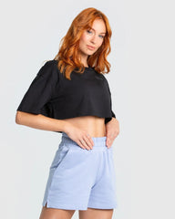 العارضة ترتدي قميص أسود قصير "Comfort Oversize Cropped Short Sleeve T-shirt" من WOMEN'S BEST وشورت أزرق.