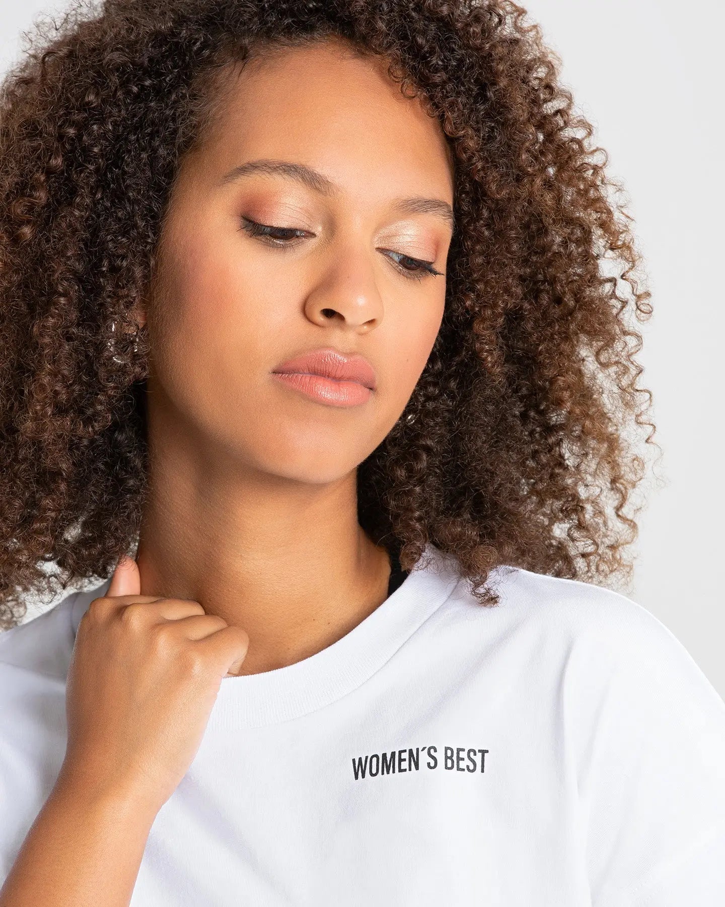 وصف: امرأة ترتدي تي شيرت أبيض من WOMEN'S BEST خلال العصر عبارة "نساء أفضل