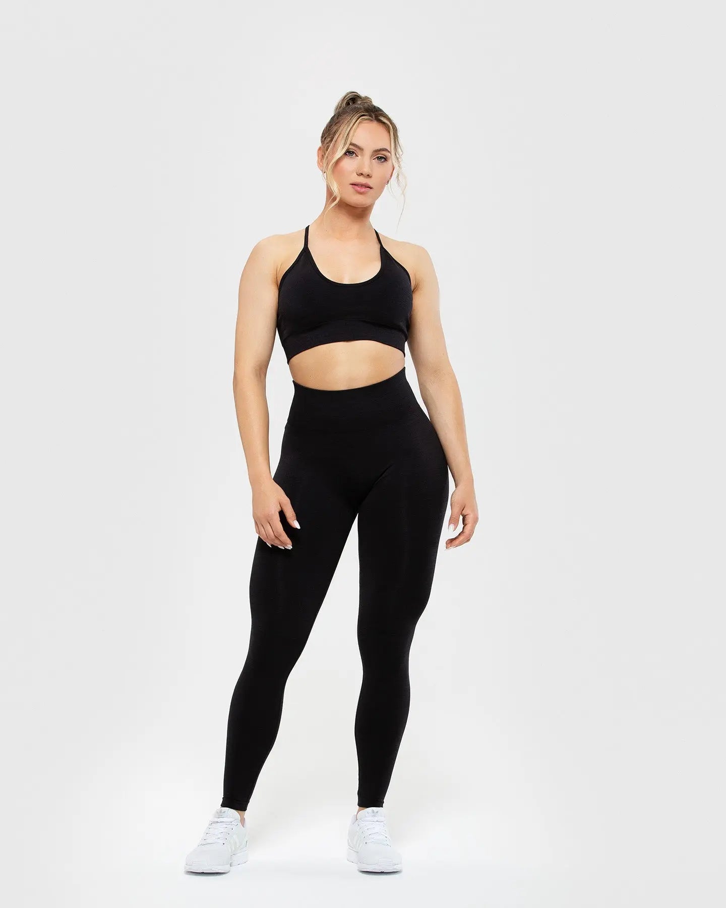 امرأة ترتدي حمالة صدر نسائية من BEST Define Seamless Racer Back باللون الأسود وبنطلون ضيق، مصنوعة من مواد عالية الجودة.