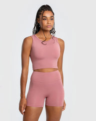 وصف: امرأة ترتدي قميص بلا أكمام Essential Crop Tank Top بلون وشورت الجسم السكني من WOMEN'S BEST - Dusty Pink.