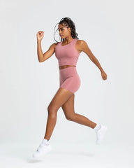 الوصف: قميص نسائي للركض "Essential Crop Tank Top" من WOMEN'S BEST بلا أكمام وشورت وردي فاتح.