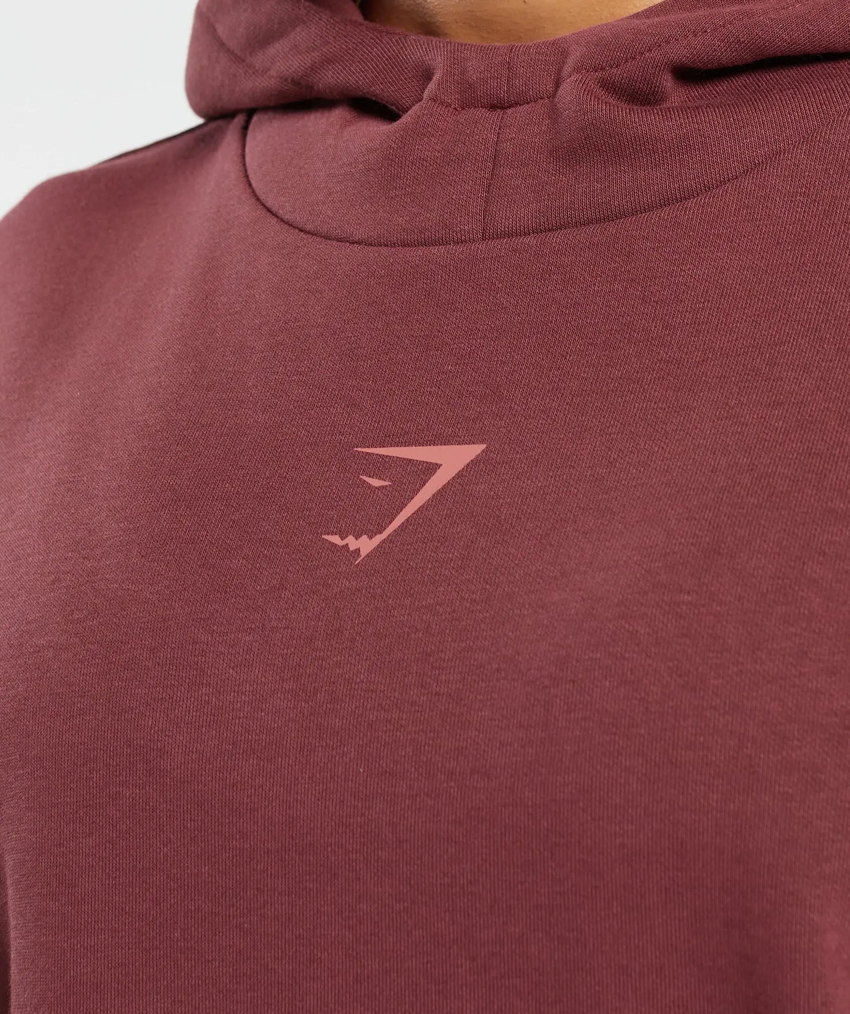 امرأة ترتدي هودي مريح وأنيق ملتزم بـ The Craft من Gymshark | United We Sweat، بشعار وردي مصنوع من مواد عالية الجودة.