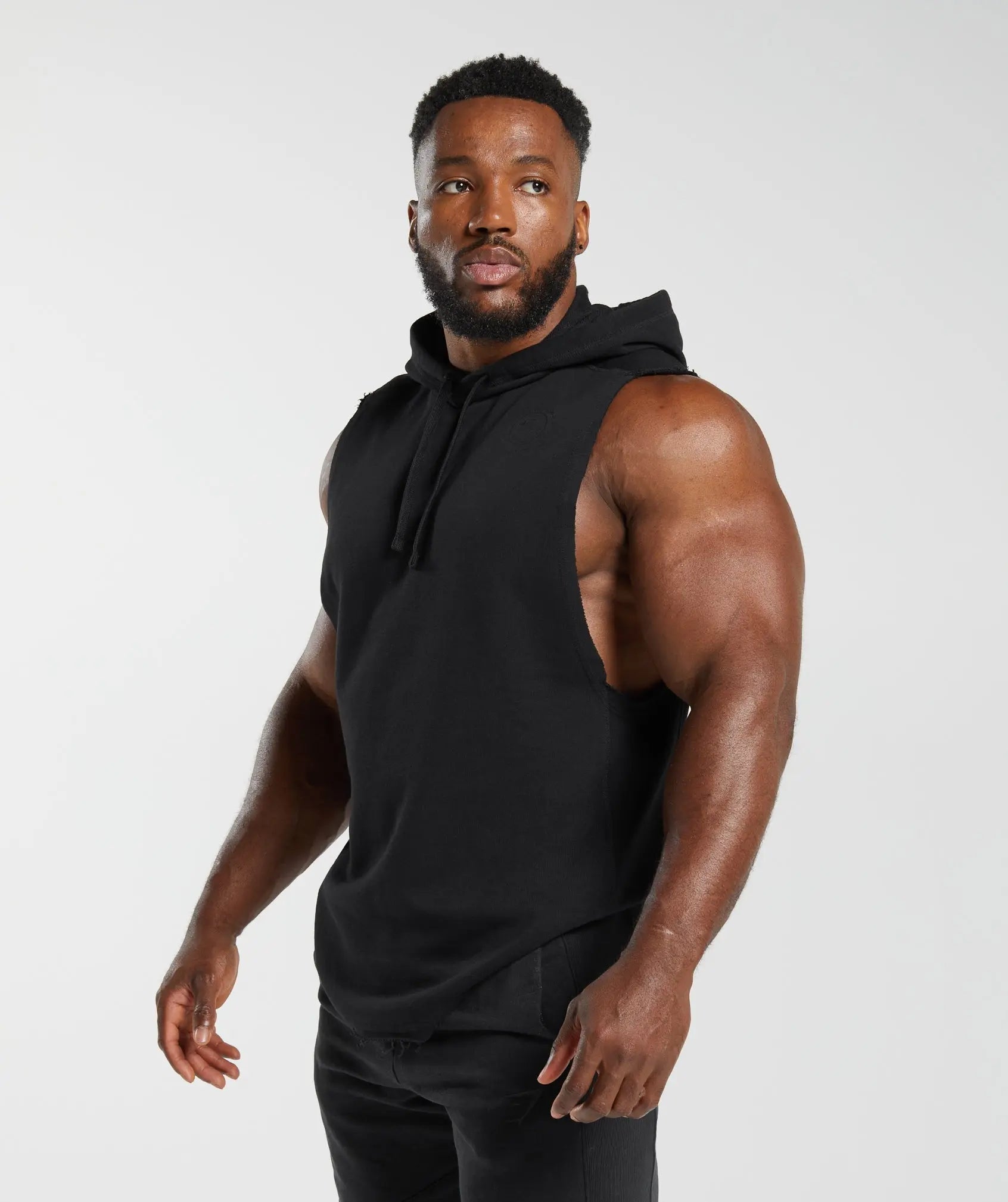 رجل يرتدي هودي Legacy Drop Arm أسود بدون أكمام بتصميم عصري من Gymshark | متحدون نحن نتعرق.