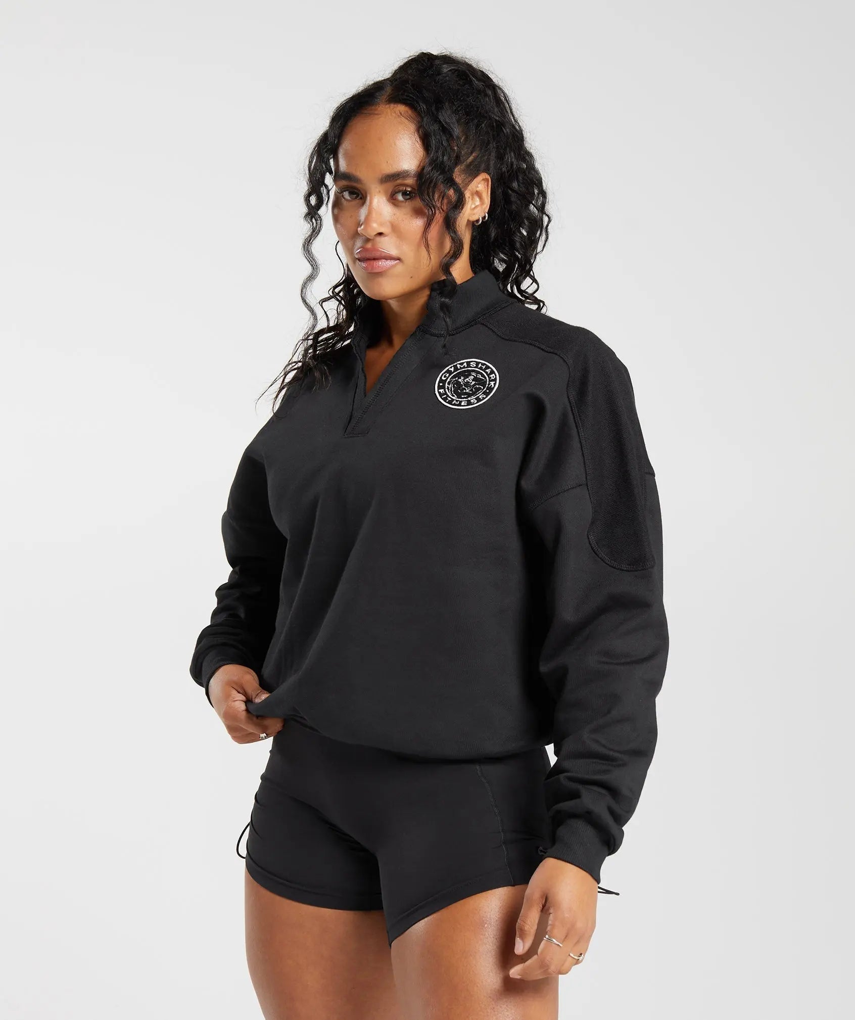 الوصف: ملابس نسائية ترتدي قميص Legacy Oversize باللون الأسود مع شورت. من جيمشارك | متحدون نحن نتعرق.