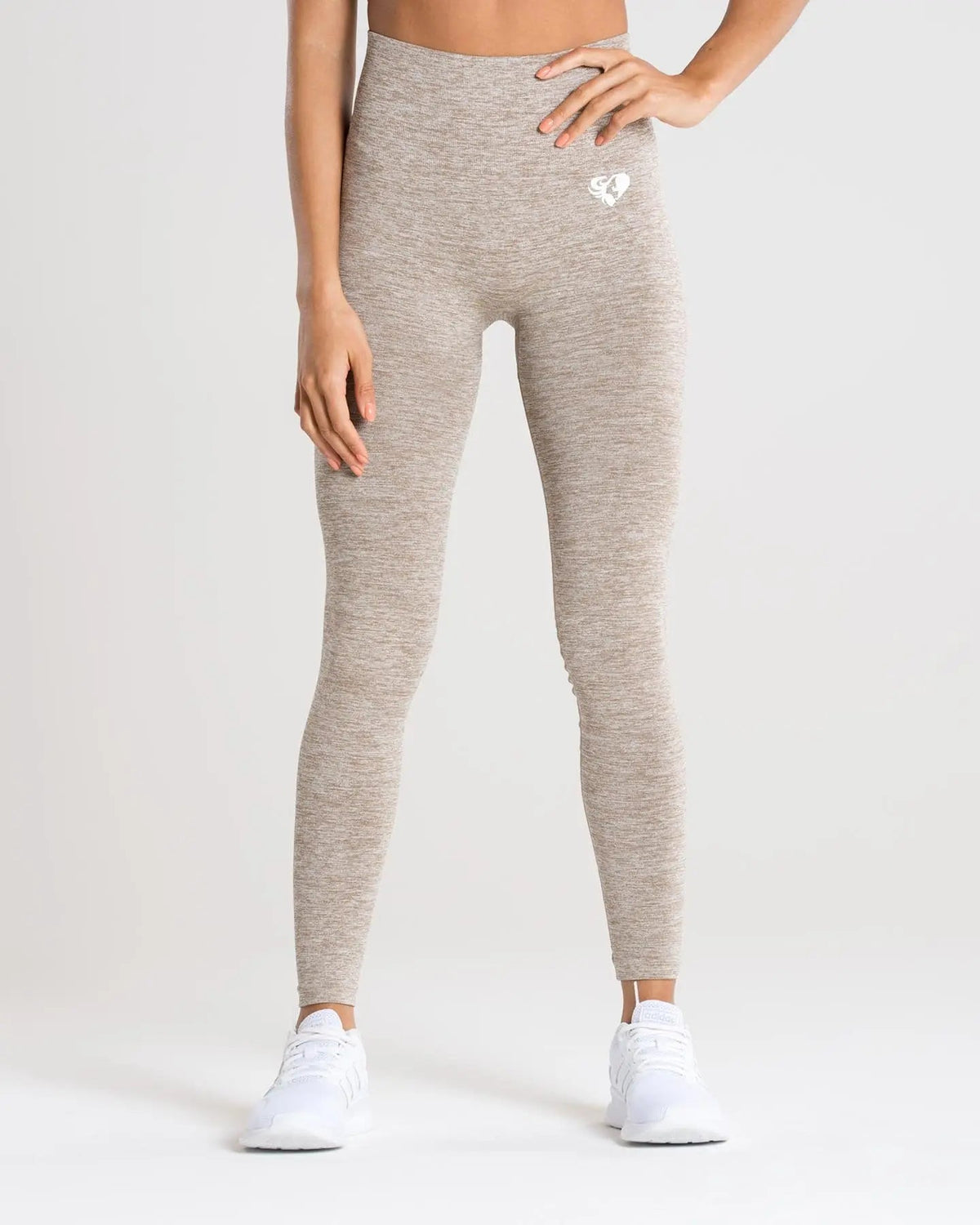 امرأة ترتدي بنطالًا ضيقًا باللون البيج وقميصًا أبيضًا، ينضح بنطال ضيق بدون خياطة من BEST WOMEN'S Move | براون غراي مارل و راحة.