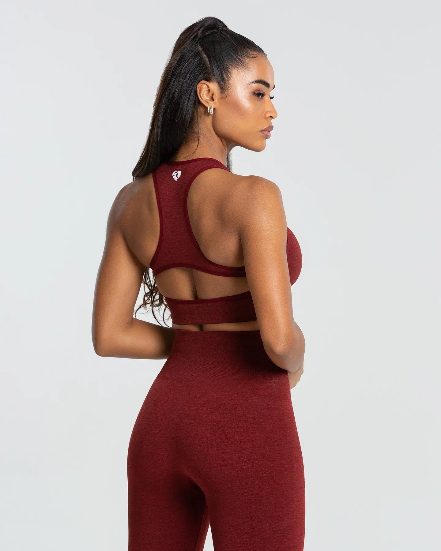 المنظر الخلفي لامرأة ترتدي حمالة صدر رياضية بدون خياطة BEST Move للنساء باللون الأحمر الياقوتي مع بنية سلسة وسراويل ضيقة.