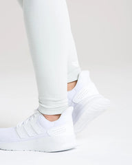 ساق امرأة في أفضل طماق نسائية بدون خياطة | حذاء جري رمادي فاتح مغسول وسراويل ضيقة بدون خياطة.