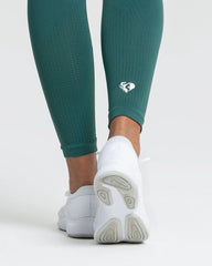 امرأة ترتدي بنطالًا ضيقًا بدون خياطة من BEST Power للنساء باللون الأخضر الغابة.