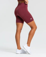 المنظر الخلفي لامرأة ترتدي شورت ركوب الدراجات BEST Power Seamless من WOMEN'S BEST باللون العنابي، مما يوضح مرونتها وقوتها أثناء ركوب الدراجة.