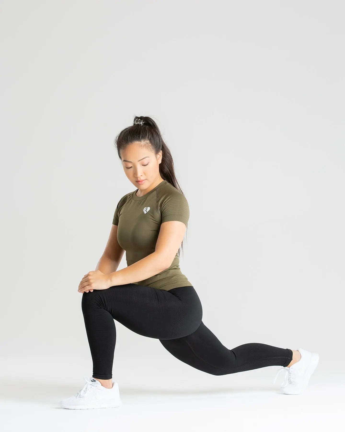 امرأة ذات تهوية ممتازة تمارس تمرين القرفصاء مرتدية تي شيرت Power Seamless | كاكي من WOMEN'S BEST.