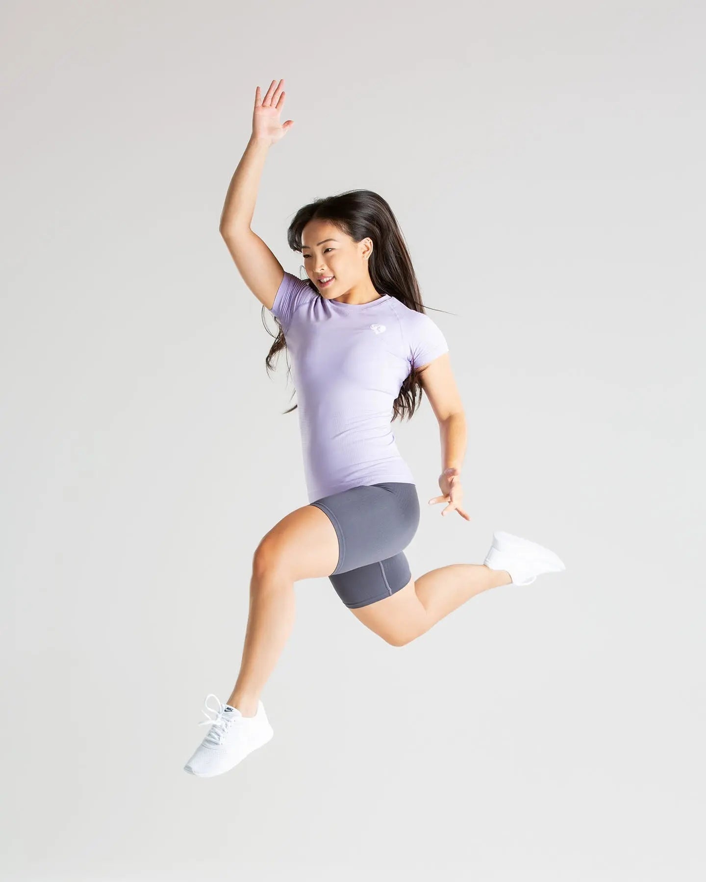 امرأة شابة ترتدي تي شيرت نسائي من ماركة Best Power Seamless Lilac تقفز في الهواء، لتستعرض الملمس الناعم ونعومة القماش.