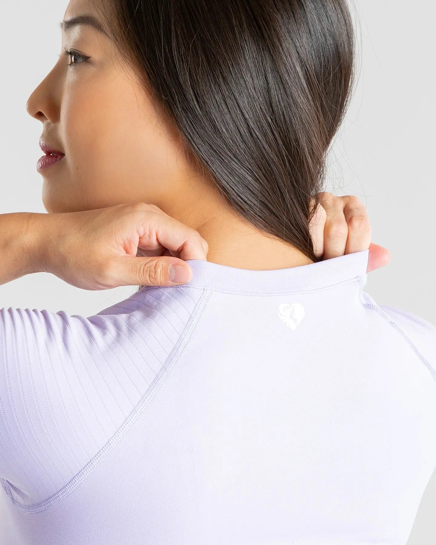 الجزء الخلفي لامرأة ترتدي تي شيرت BEST Power Seamless للسيدات باللون الأرجواني الفاتح بملمس ناعم.