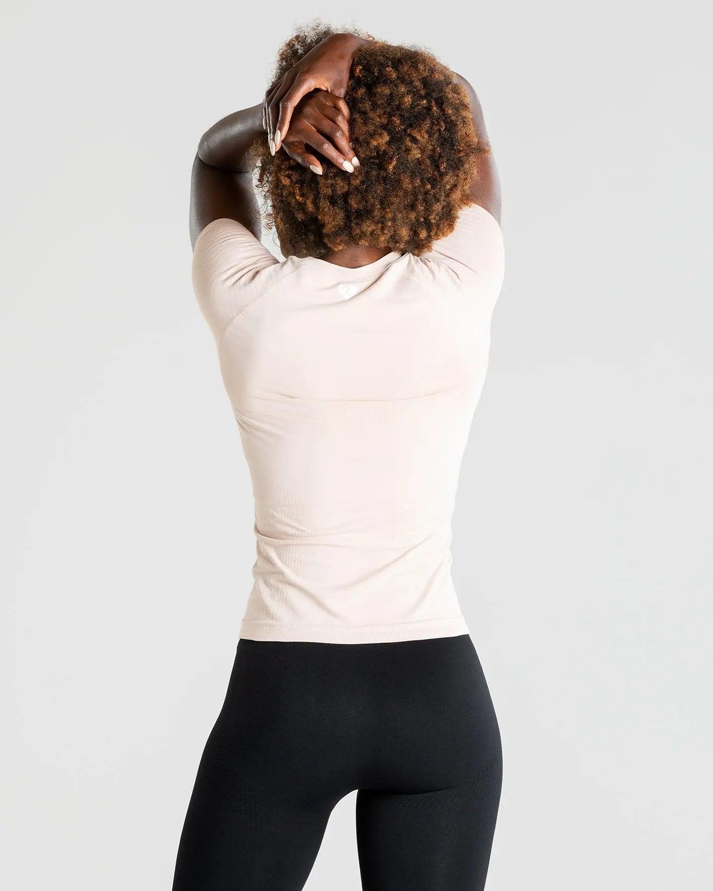 الجزء الخلفي لامرأة ترتدي طماق سوداء وتي شيرت نسائي بدون خياطة من BEST Power | ناقص.